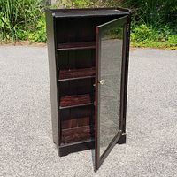 Front angled view of the antique wooden cabinet with glass door open showing three removable shelves inside.