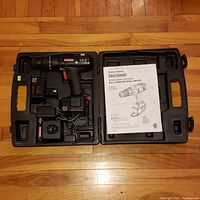 Craftsman cordless drill-driver set inside black hard plastic case with two 12.0V batteries, charger, power adapter, and owner's manual visible