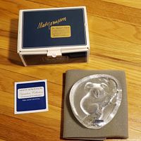 Paperweight along with its original box and certificate card placed beside it on a wooden floor.