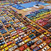 Hundreds of assorted diecast cars arranged by color and type on the floor.