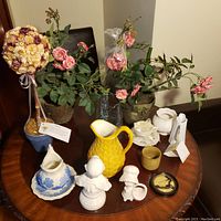 Overview of artificial plants and various ceramic decorative items on round table