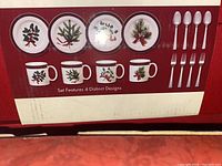 Photo of box packaging showing 4 distinct Christmas-themed designs on mugs and plates, plus spoons and forks