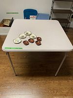 Full view of folding card table with four wooden nut bowls and four ceramic playing card plates on the top surface.