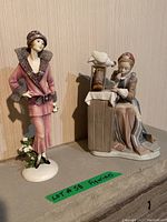 Two porcelain figurines side by side on ledge