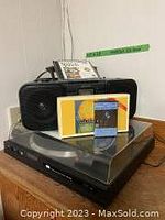 Photo showing Sunsui turntable with clear dust cover and tone arm, Sony CD cassette player with two speakers, and several cassette tapes and CDs.