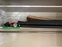Photo showing four compact umbrellas and part of walking cane on a shelf, along with boot mats stacked behind.
