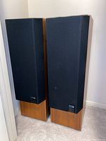 Pair of speakers on carpeted floor with grills installed