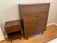 Wide angle photo showing both tallboy dresser and bedside table side by side against wall on wooden floor.