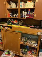 Overview of wooden cabinets storing tools, hardware and maintenance items including tape rolls, cans, and boxes of screws and nails.