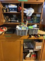 Photo of shelves holding a white boxed glue gun, copper tubing coils, assorted small boxes and cans, rolls of tape, gloves, and miscellaneous hardware and pest control items.