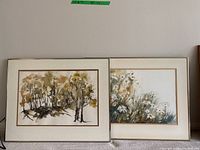 Two framed watercolor paintings by Elizabeth Gibson side by side. One depicts a tree scene, the other a floral scene.