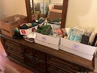 Wide photo showing the dresser top holding multiple boxes, small photo frames, and various small items above a wooden dresser.