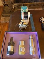 Photo of Avon Grey Flannel gift set with bath shower gel, deodorant, and after shave lotion bottles in a purple box with vintage-style clock and other fragrance bottles nearby.