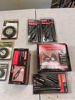 Overview of lot items on table including boxed sander, impact accessory sets in blister packs, and abrasive circular brushes.