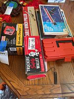 Photo showing multiple boxed items including a cable winch puller, Craftsman charger, and safety wallet on a wooden table.