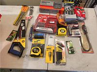 Overview photo showing all tools and items arranged on table, including saw, brushes, drill bit sets, tapes, tester, and other accessories.