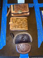 Four leather wallets laid out on surface showing front craftsmanship and tooled leather detail.