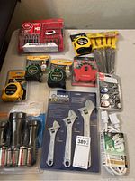 Photo showing Milwaukee Shockwave bit set, tape measures, screwdrivers, adjustable wrenches, RAM keychain lighting, and extension cord.