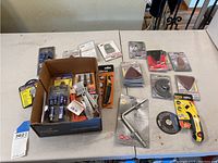 Full lot displayed on table, showing boxed items, sanding pads, and assorted tools.