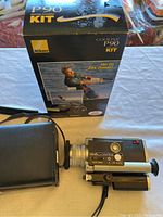 Nikon Coolpix P90 kit box with vintage Minolta AutoPak-8 D6 movie camera and camera case on table