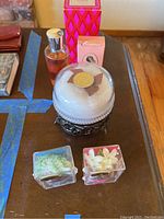 Overview of perfume collection on table showing several bottles and boxes including round glass container, pink Avon box, and tall pink box.