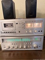 Realistic TX 497 cassette tape player stacked above Fisher TX 4372 stereo receiver and two Realistic speakers on top.