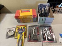 Photo showing the red and gray toolbox, box with Kobalt 3 piece pliers, and other tools on the table