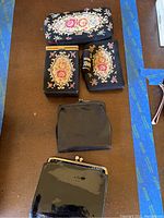 Lot of six purse accessories including embroidered fabric items and shiny black vinyl coin purses on a wooden table.