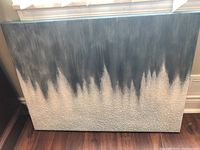 Full image of the abstract painting leaning against a wall, showing the gradient from black at the top to heavily textured light gray bottom.