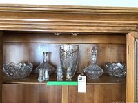 Full view of the set showing all seven items on a wooden shelf: two cut glass bowls, tall crystal vase, two decanters, salt and pepper shakers