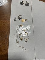 Photo showing entire lot of mixed gold jewelry pieces on white paper.