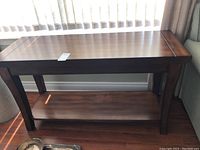 Wood hall table with a medium brown wood finish, straight legs, and a rectangular top surface. Lower shelf visible. Scratches noted on the table surface.