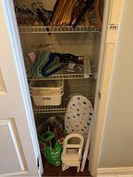 View of closet containing wooden, plastic and fabric-covered hangers on two shelves. Storage bins and laundry items on lower shelf.