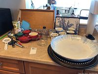 Overview of kitchen items including mugs, soufflé containers, mason jars, serving tray, platters, and utensils on countertop