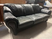 Front view of three-seat dark green leather sofa showing overall style and cushion layout
