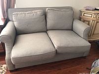 Front view of 4 cushion loveseat with grey fabric upholstery, visible small marks on cushions, showing overall condition and design