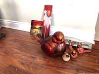 Wide view of lot contents showing the large red bird figurine, three smaller cardinal figurines, and two tile wall art pieces leaning against the wall