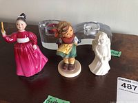 Two Goebel figures, two Rosenthal glass tea light holders, and one small Royal Doulton figurine visible on wooden surface.