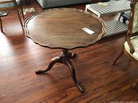Full view of the round pedestal table showing fluted edges on top and three legs.