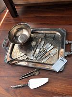 Silver plate serving set on tray including bowl, knives, tongs, and utensils