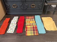 Photo showing six sets of folded linen napkins in various solid colors and patterns.