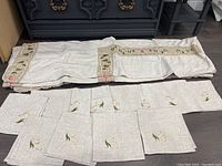 Full view of the linen tablecloth and 12 matching napkins laid out on the floor showing their size and embroidered details.