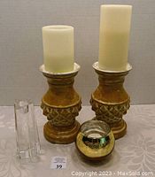 Photo of four candle holders on a patterned cloth surface including two wooden holders with battery-operated candles, a clear glass rectangular holder, and a small round decorative glass holder.