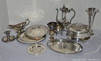 Image showing all silver plated serving pieces including trays, coffee pot, covered casserole with glass insert, goblet, gravy boat, and candlestick.