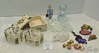 Photo of all items in the lot arranged on a white tray showing the range of collectible figurines and decorative objects including the ceramic trinket box and jewelry.