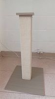 Front view of cat scratching post showing woven sisal wrapped vertical post on wooden base.