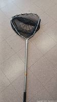 Fishing net with black mesh and metal frame attached to a telescoping aluminum pole with grip handle.