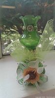 Photo showing the green glass oil lamp with floral decorations and green mesh on the base.