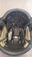 Interior view of the ice hockey helmet showing black foam padding and chin strap with buckle.