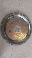 Top-down photo of the round tray showing the copper design with silver edge and braided rim.